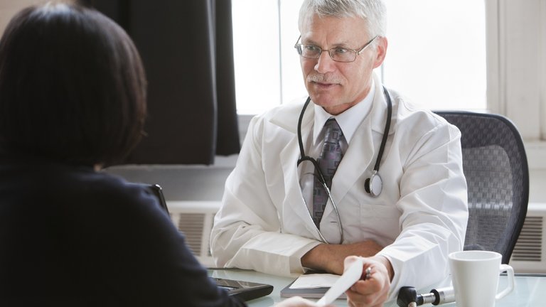 El médico le entrega una receta a la paciente