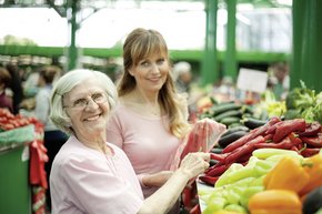 Mujeres que hacen compras las verduras en un mercado 