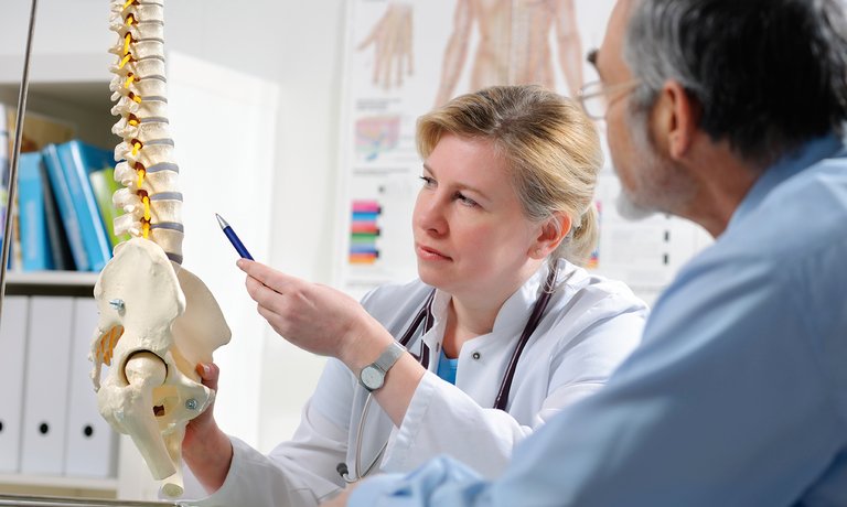 Médico explicando al paciente las posibles complicaciones metabólicas de la enfermedad ósea debido a la ERC.